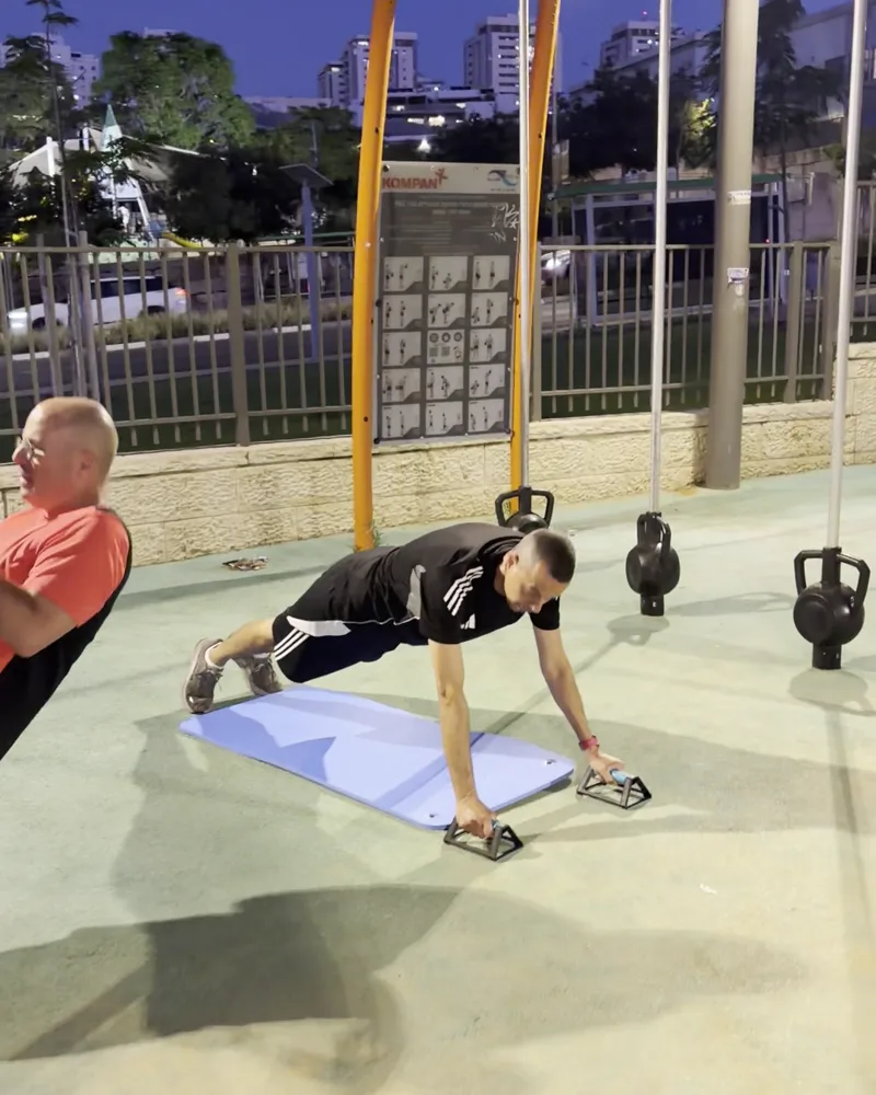 מתאמן מקבוצת האבות בתרגיל שכיבות סמיכה, עם המאמן לצידו